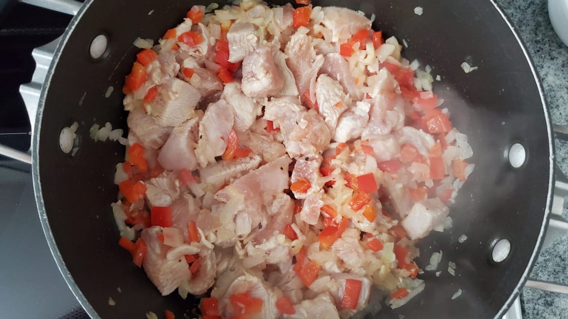 Mixing the chicken with onions, garlic and red pepper.