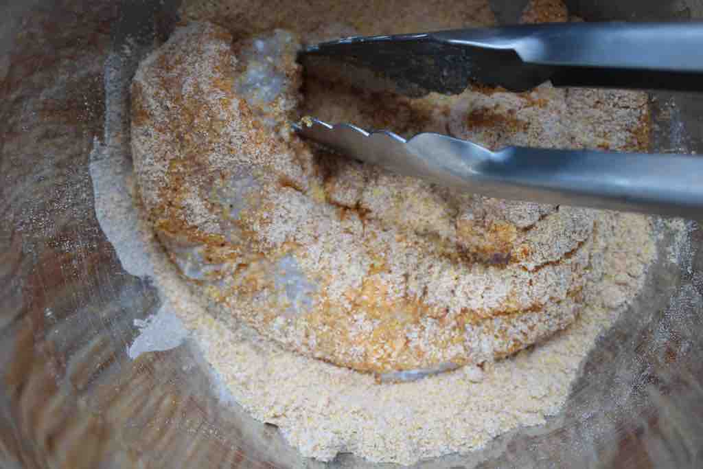 Coating the catfish fillets with cornmeal.