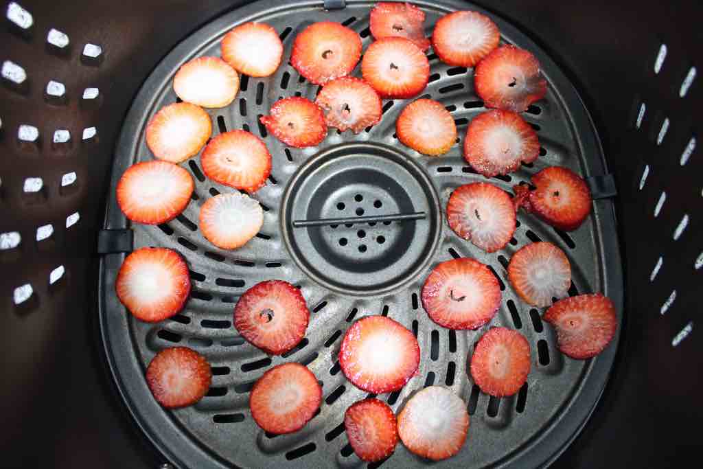 Place the strawberries inside of the air fryer to begin dehydrating.