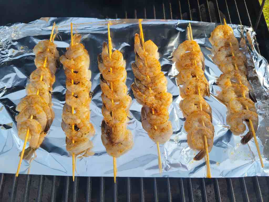 Insert the shrimp into the skewers, season them and cook them on the bbq grill over aluminum foil as shown in the photo.