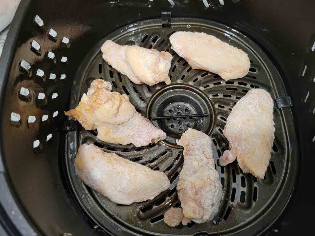 Transfer the wings into the air fryer and cook.