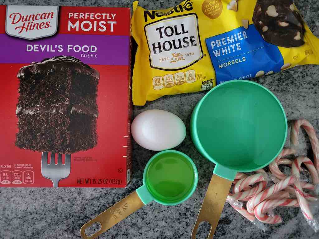 The ingredients needed for this recipe are boxed chocolate cake mix, white chocolate chips, egg, water, oil and candy canes.