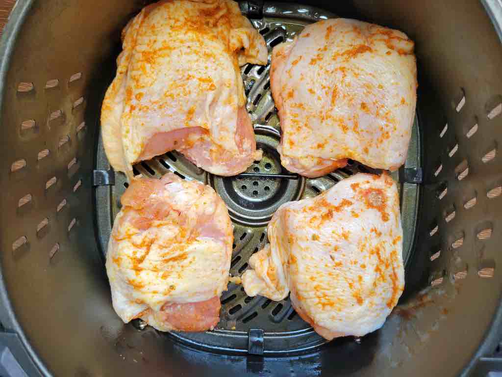 Season the chicken thighs and place them in the air fryer to cook as shown in the photo.
