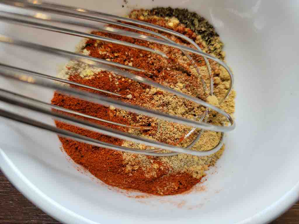 Whisk together the 11 herbs and spices that make up the ingredients in this recipe. They must be mixed together until fully combined as shown in this picture.