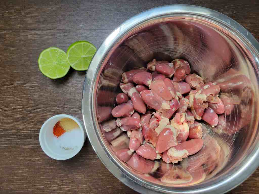 The ingredients needed for this recipe are chicken hearts or gizzards, lime juice, salt, pepper, granulated garlic, paprika powder, dried parsley and fresh parsley for garnishing as shown in the photo.