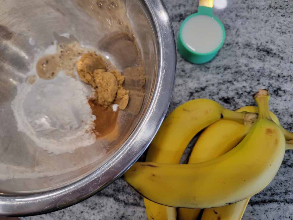 The ingredients needed for this recipe are bananas, flour, baking powder, baking soda, salt, cinnamon, brown sugar, vanilla extract and milk.