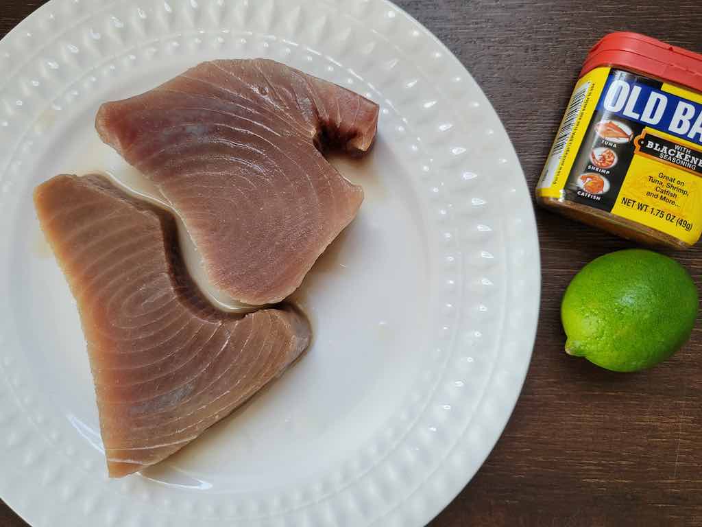 The ingredients needed for this recipe are yellowfin tuna steaks, lime juice and old bay blackened seasoning.
