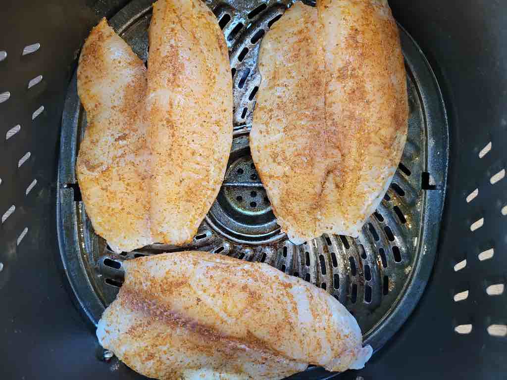 Season the tilapia on all sides and transfer to the air fryer to cook as shown in this photo.