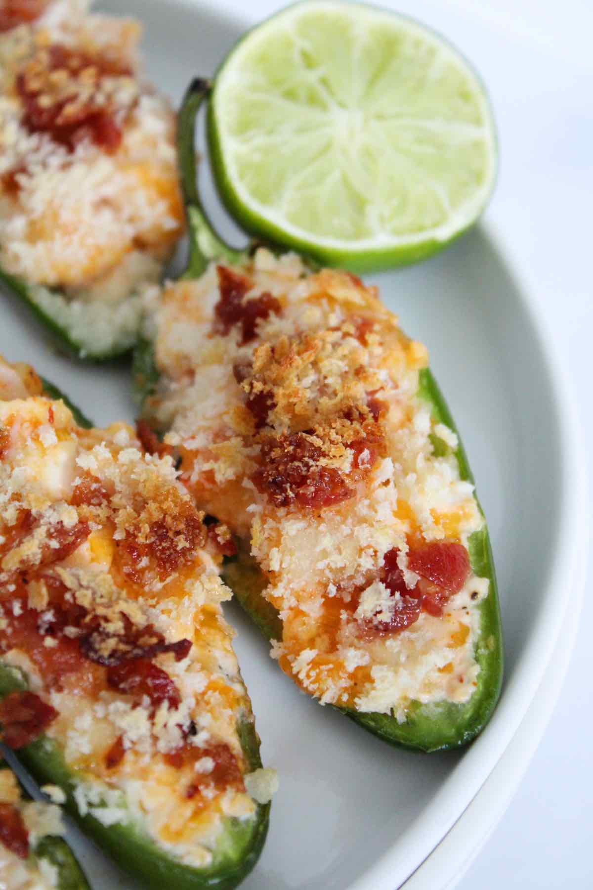 Serving shrimp stuffed jalapeno poppers with fresh lime on the side.